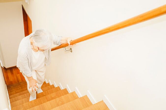 Frau mit Schmerzen beim Treppensteigen