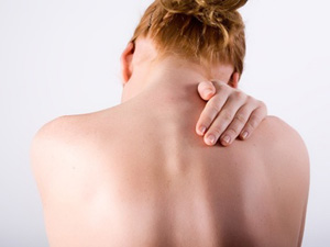 Ung kvinna rör vid en smärtsam punkt på ryggen